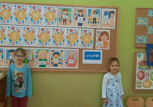 Dziewczynki na tle tematycznej tablicy z Prawami dziecka