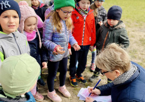 Dzieci wymieniają oznaki wiosny, nauczyciel zapisuje je na kartce