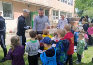 Pan Robert rozdaje zdjęcia z wizerunkiem piłkarzy dzieciom