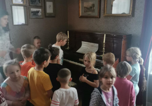 Dzieci oglądają pianino znajdujące się we dworze