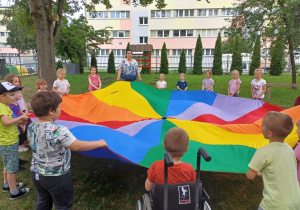 Dzieci biorą udział w zabawie z chustą animacyjną