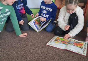 Dzieci oglądają książki przyniesione przez swoich rodziców