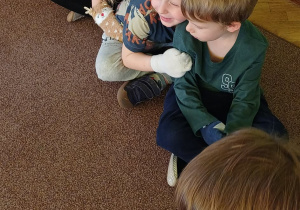 Frebelki wykonują masaż nałożonymi na dłonie skarpetkami o różnej fakturze