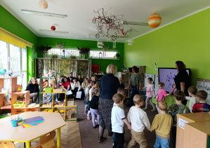 Dzieci z nauczycielami tańczą w kole śpiewając powitankę