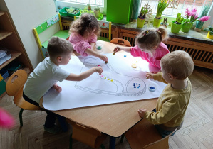 Dzieci stemplują szablon buta w kąciku twórczym