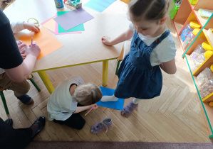 Chłopiec mierzy długość stopy dziewczynki podczas aktywności w kąciku badawczym.