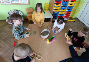 Dzieci uczą się wiązać buty w kąciku gospodarczym