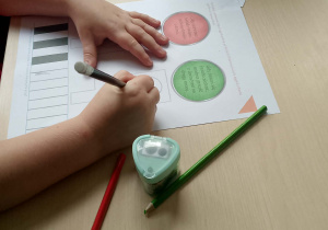 Dziecko wykonuje kartę pracy - kolorowanie świateł sygnalizatora