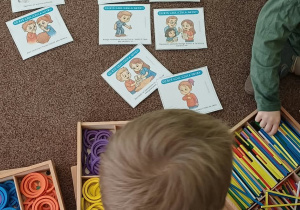 Dzieci przyglądają się obrazkom przedstawiającym różne emocje