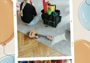 Dzieci z Panią siedzą w kole i grają na instrumentach