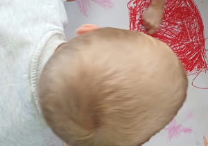 Dzieci siedzą dokoła dużego kartonu i wspólnie rysują