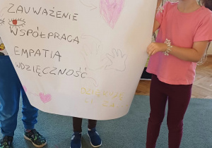 Dzieci trzymają plakat i prezentują prace