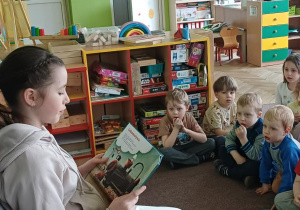 Absolwentka przedszkola czyta dzieciom