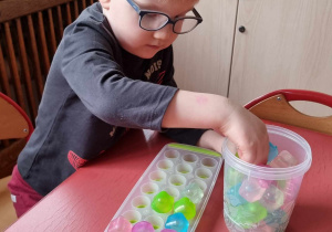 Chłopiec wkłada kostki do foremki według kolorów