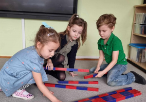 Dzieci układają belki numeryczne wg pedagogiki M. Montessori