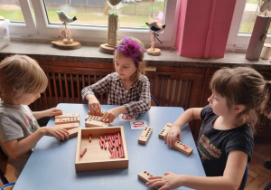 Dzieci przeliczają drewniane kołeczki i dopasowują je do odpowiedniej cyfry