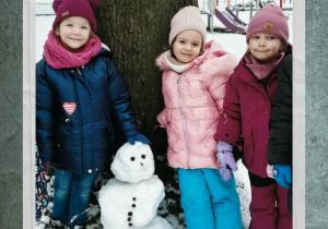 Dzieci pozują do zdjęcia z bałwankiem