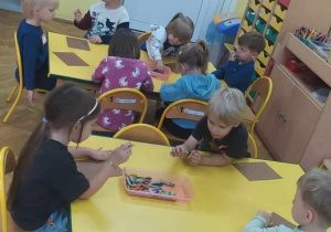 Dzieci tworzą prace plastyczne przy stolikach