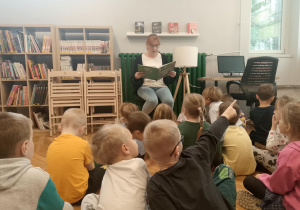 Dzieci słuchają opowiadania czytanego przez panią bibliotekarkę