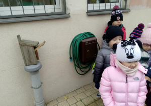 Dzieci stoją przy starej budce lęgowej