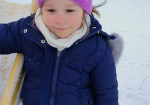 Dziewczynka stoi przy zjeżdżalni zimową porą