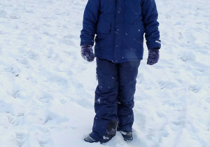 Chłopiec stoi w ogrodzie przedszkolnym zimową porą