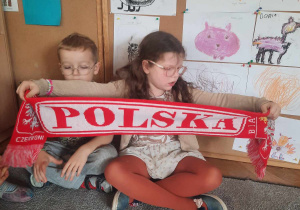 Dziewczynka trzyma szalik z napisem Polska