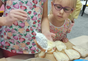Dziewczynka nakłada na kanapkę twarożek własnej roboty
