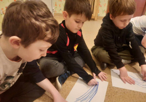 Chłopcy rysują wiązki za pomocą niebieskiej kredki pastelowej