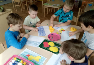 Chłopcy kreślą za pomocą kredek pastelowych staw