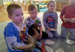 Chłopiec trzyma gumową zabawkę przedstawiającą pterodaktyla