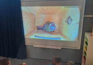 Dzieci oglądają film edukacyjny pt. :,,Z wizytą w budce lęgowej sikorek"
