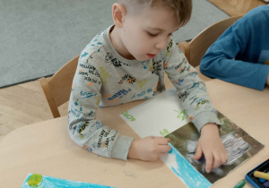 Chłopiec robi pracę plastyczną nt.sowy