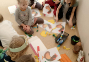 Dzieci ozdabiają ogon koguta bibułą