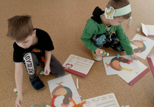 Chłopcy ozdabiają ogon koguta bibułą